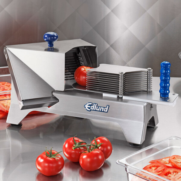An Edlund tomato slicer on a counter with sliced tomatoes in a clear container.