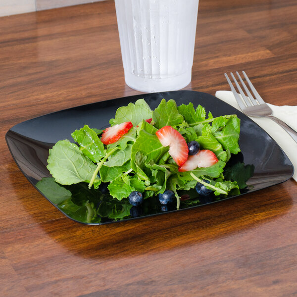 A Fineline black plastic salad plate with a salad on it.