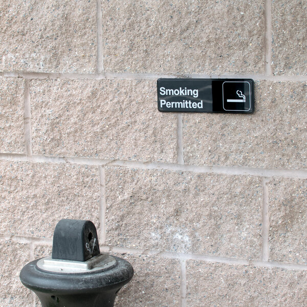A black and white Thunder Group Smoking Permitted sign on a wall.