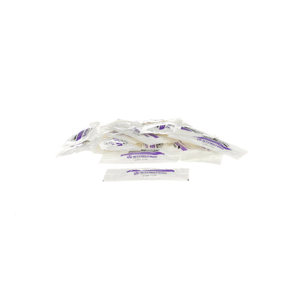 A pile of white and purple packets of Stoelting by Vollrath lubricant on a white surface.