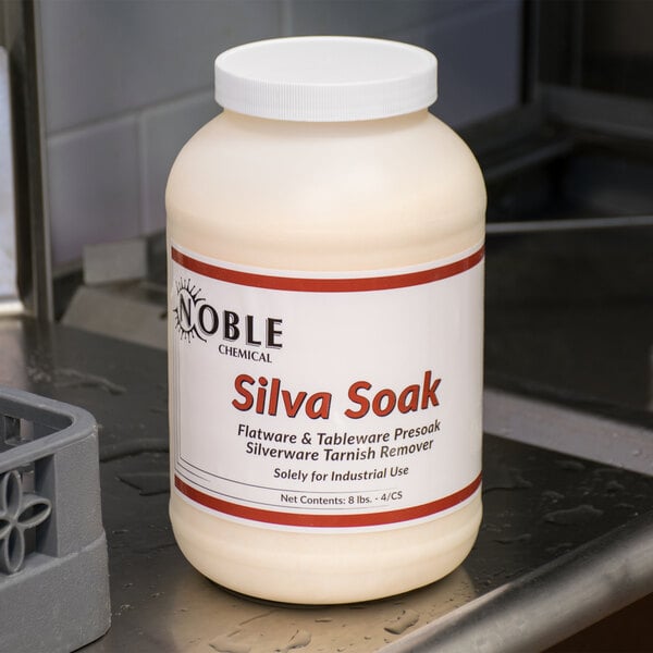 A white bottle of Noble Chemical Silva Soak Concentrated Presoak Powder on a metal surface.