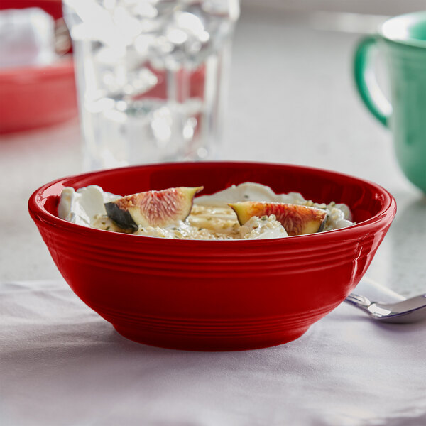 A red Tuxton nappie bowl filled with yogurt and fruit.
