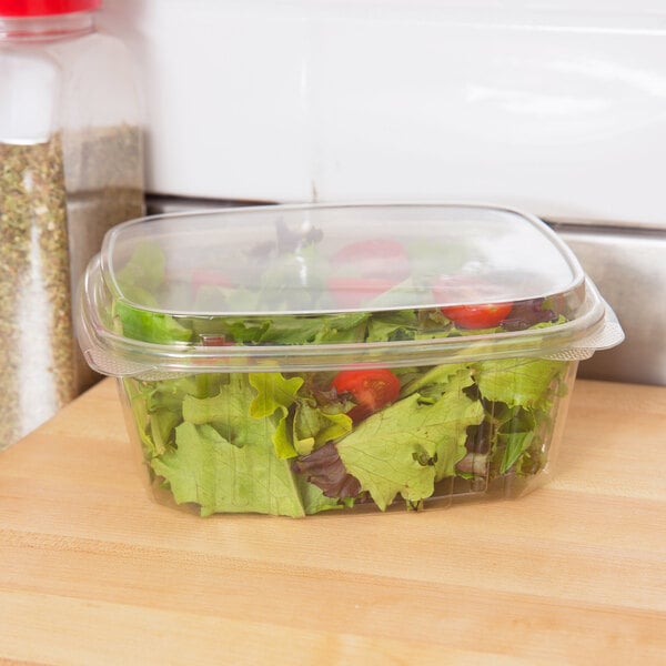 A Genpak clear hinged deli container with a salad inside.