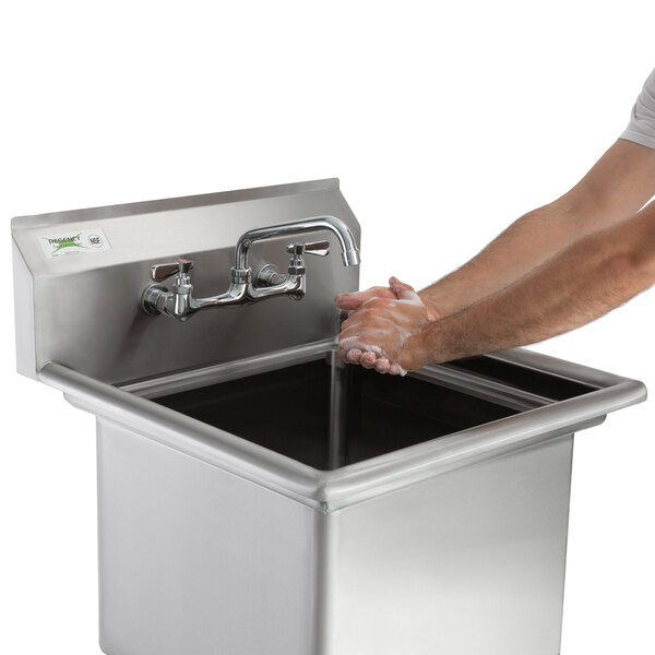 A person washing their hands in a Regency stainless steel sink on a counter.