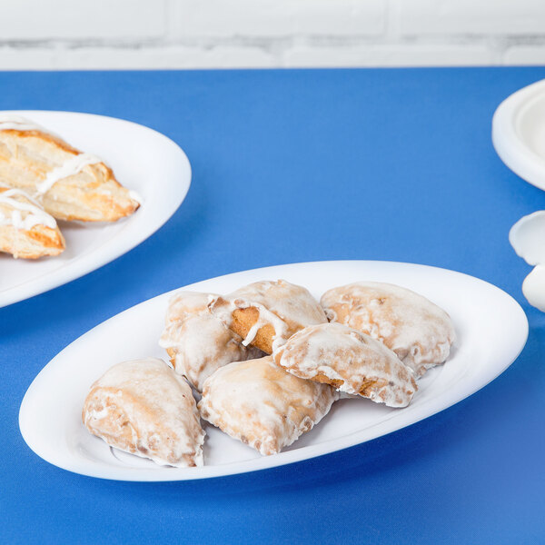 A white plastic oval tray with pastries on a blue table.