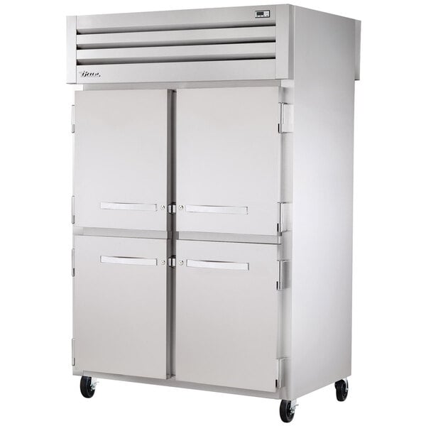 A True Spec Series stainless steel pass-through refrigerator with half solid front and glass back doors.