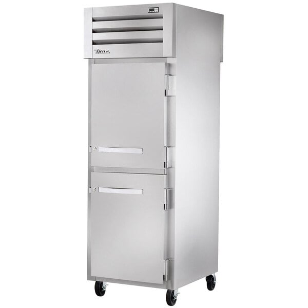 A stainless steel True pass-through refrigerator with one solid front half door and one glass back full door with silver handles.