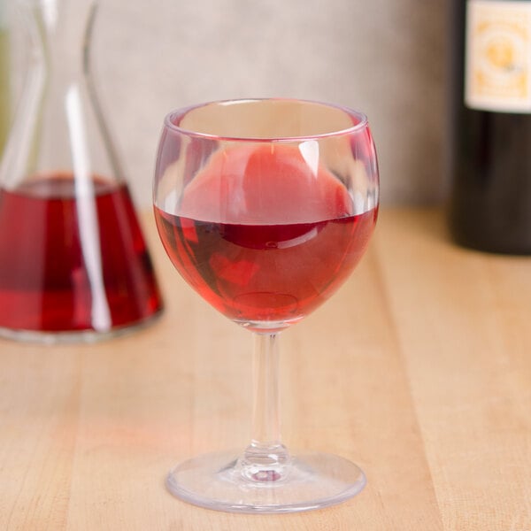 A GET SAN plastic wine glass filled with red wine on a table.