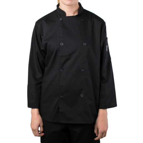 A woman wearing a Mercer Culinary Genesis black long sleeve chef jacket.
