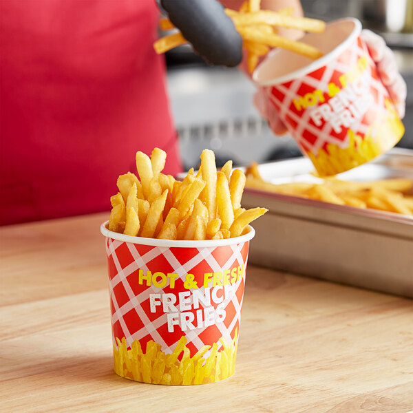 A hand holding a Choice French Fry Cup filled with french fries.