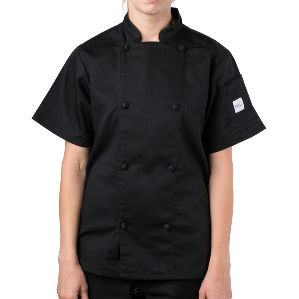 A woman wearing a black Mercer Culinary short sleeve chef jacket.