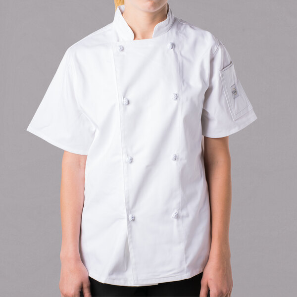 A young woman wearing a white Mercer Culinary short sleeve chef jacket with cloth knot buttons.