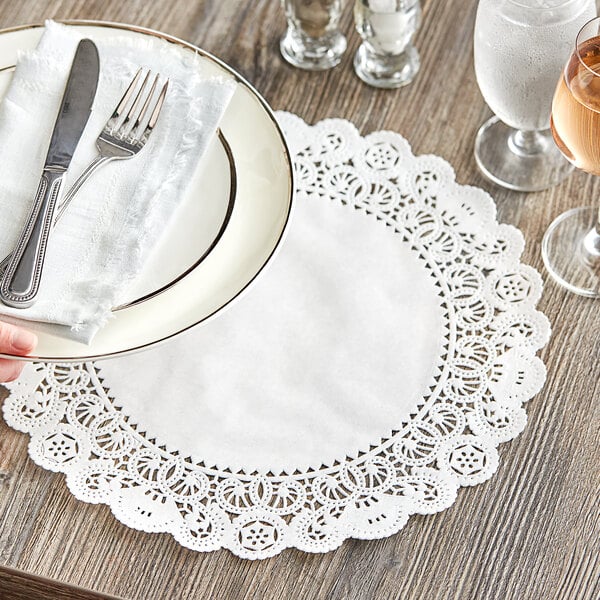 A hand holding a plate with silverware on a white Normandy lace doily.