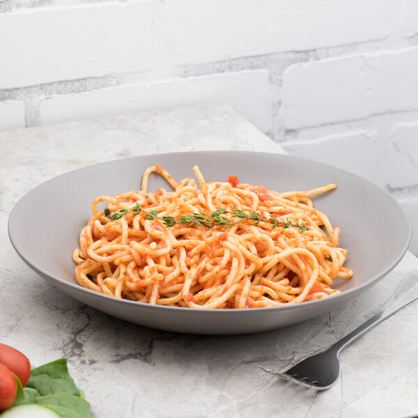 A 10 Strawberry Street matte wave stoneware plate with spaghetti and tomato sauce with a fork.