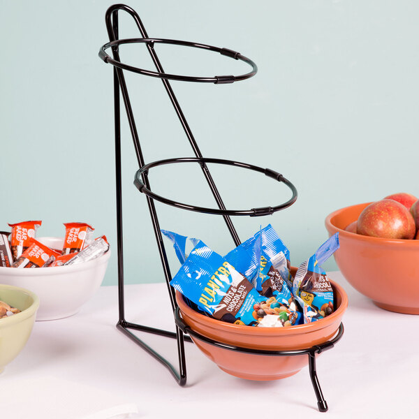 A black metal Cal-Mil three tier bowl stand holding bowls of food on a table.
