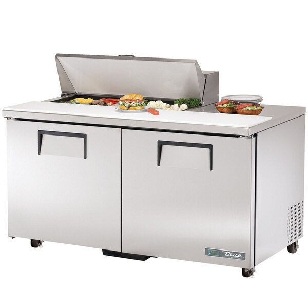 A True refrigerated sandwich prep table with two doors on a counter with food.