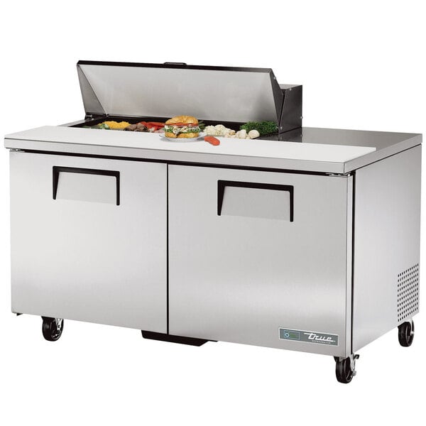 A True refrigerated sandwich prep table with food on top.