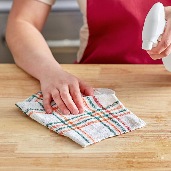 A person using a Choice striped cotton waffle-weave dish cloth to clean a table.