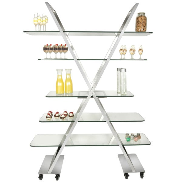 An Eastern Tabletop stainless steel rolling buffet cart with glass shelves holding food.
