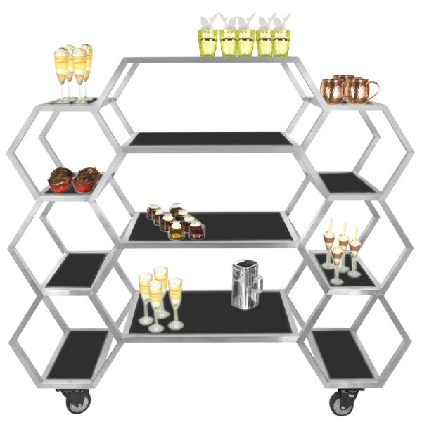 An Eastern Tabletop stainless steel rolling buffet with black acrylic shelves holding drinks and glasses.