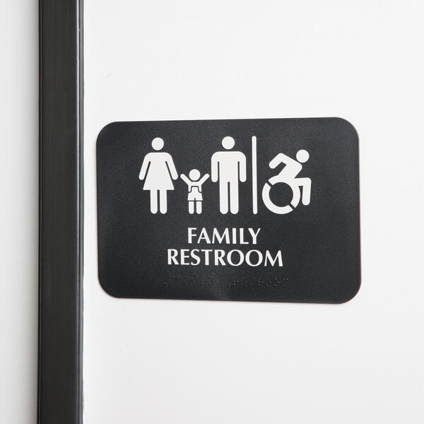 A Tablecraft ADA restroom sign with Braille for a family and wheelchair accessible restroom, in black and white.