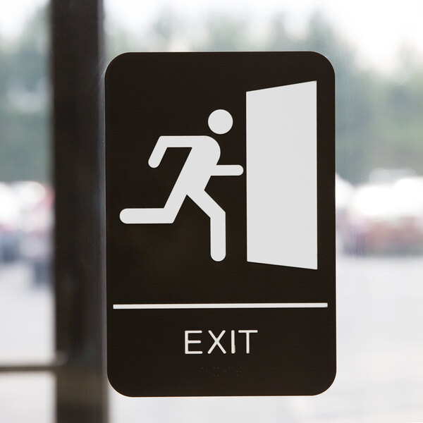 A black and white ADA exit sign with a person running out of a door.