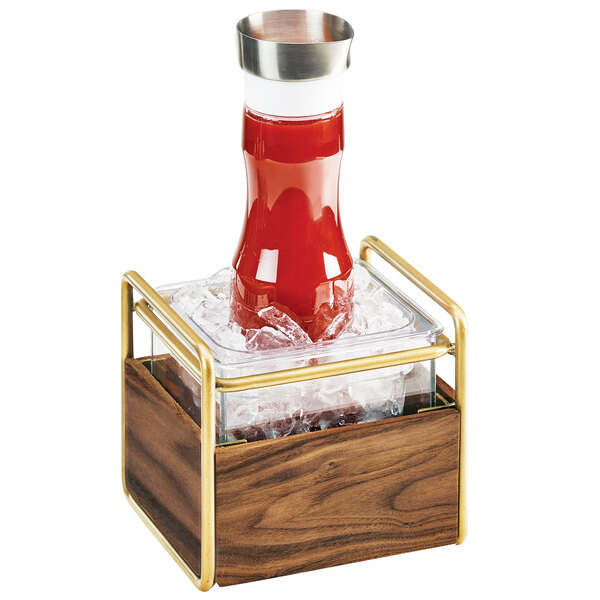 A Cal-Mil Mid-Century ice housing with a clear plastic pan of ice on a table with a glass of red liquid inside.