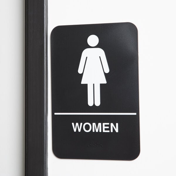 A white Thunder Group ADA women's restroom sign with a woman figure and Braille.