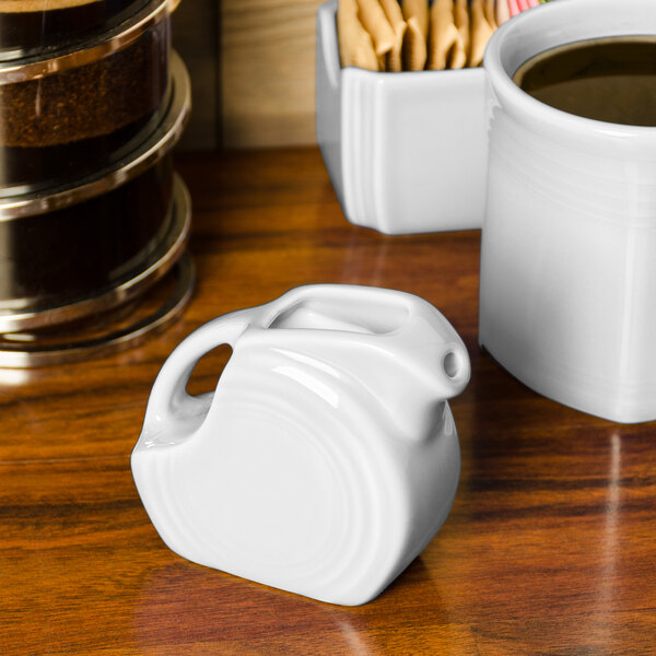 A white Fiesta® mini disc ceramic creamer pitcher on a table.