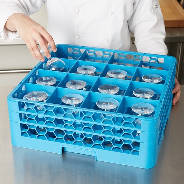A woman placing clear glasses in a blue Carlisle glass rack.