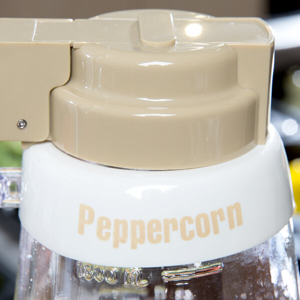 A white Tablecraft plastic salad dressing dispenser collar with beige lettering reading "Peppercorn" on it.