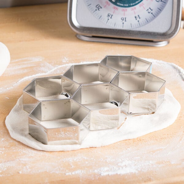 Stainless steel Ateco hexagon cookie cutters linked together.