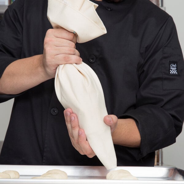 A person holding an Ateco canvas pastry bag filled with dough.