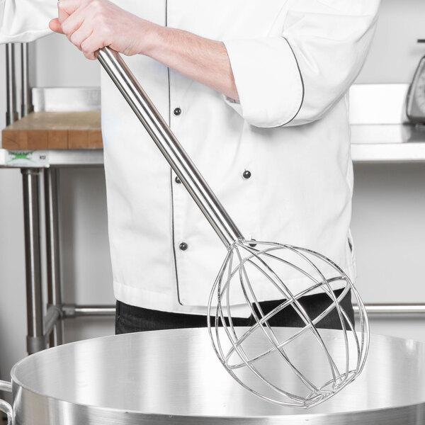 A person using a Thunder Group stainless steel ball kettle whisk in a large pan.