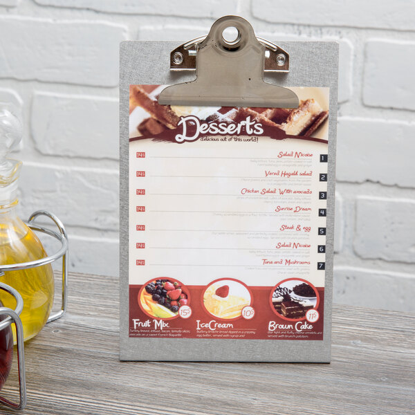 A Menu Solutions aluminum table tent with a menu on it next to a cup of coffee on a table in a bakery display.
