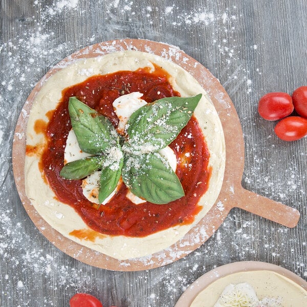 An American Metalcraft round pizza peel with a pizza topped with tomatoes and basil leaves.