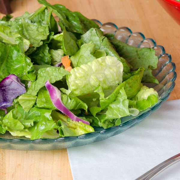 A bowl of salad in a jade polycarbonate deep plate on a table.