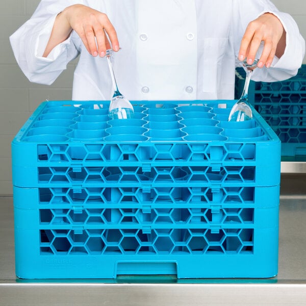 A woman in a white lab coat holding a Carlisle blue plastic glass rack with extenders.