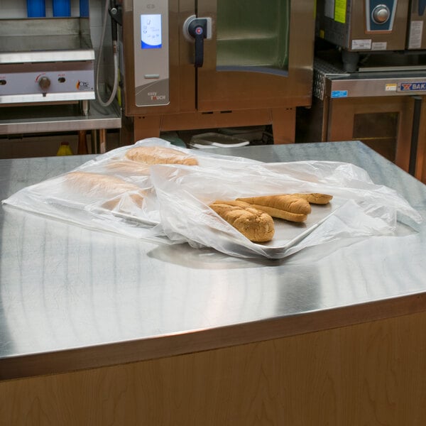 A roll of LK Packaging Bun Pan Covers on a tray of bread on a counter.