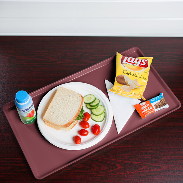 A Cambro raspberry cream dietary tray with a sandwich, chips, and a drink on it.