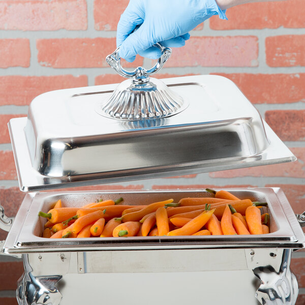 A person in blue gloves using a Choice Classic chafer cover to hold a tray of carrots.