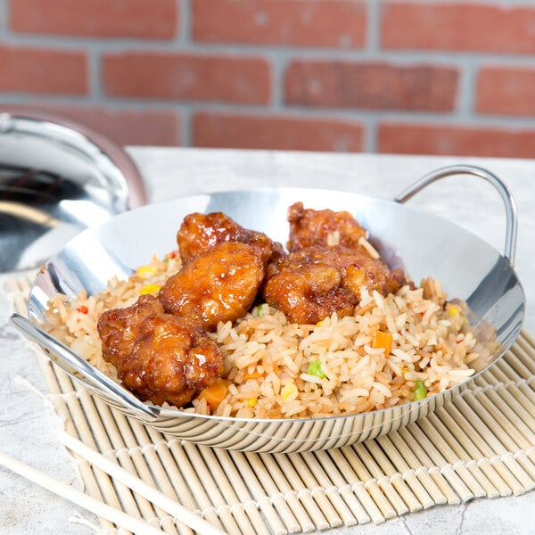 A Thunder Group stainless steel wok serving dish filled with rice and chicken on a table in an Asian cuisine restaurant.