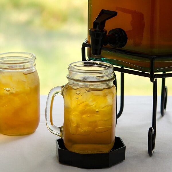A table with a pitcher of iced tea and two mason jars filled with yellow liquid.