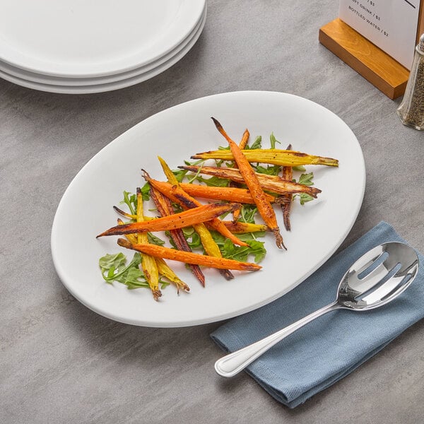 An Acopa bright white oval stoneware platter with food and a fork on a table.