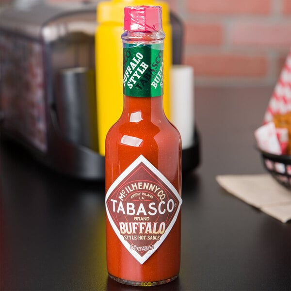 A bottle of TABASCO Buffalo Style Hot Sauce on a table.