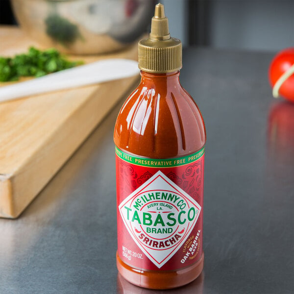A bottle of TABASCO Sriracha Hot Sauce on a counter.