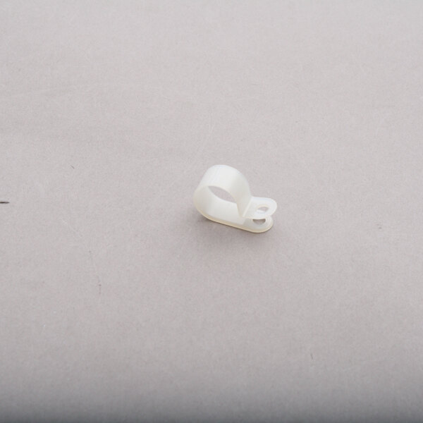 A white plastic clip on a grey surface.