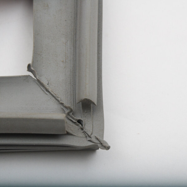 A close-up of a corner of a silver metal door gasket.