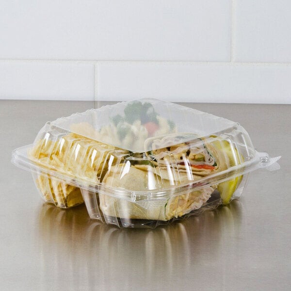 A Dart clear hinged plastic container with 3 compartments holding food.