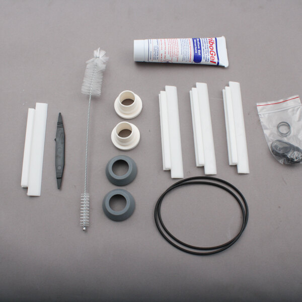 A SaniServ tune-up kit with various parts including a white object with a hole in it.